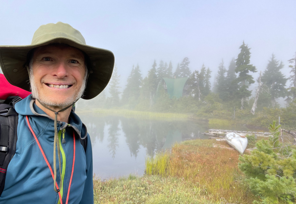 arne-pedersen-hypnotherapy-victoria-kludahk-trail-fog-cabin-calm Arne Pedersen standing at a foggy cabin along the Kludahk Trail on Vancouver Island—symbolizing the quiet inner journey of hypnotherapy.